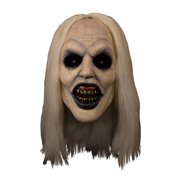 Mask, front view.  Long, straight blond hair, pale skin, veins showing through.  Large empty black eyes.  Mouth open showing dark red gums dirty yellow teeth, black lips.