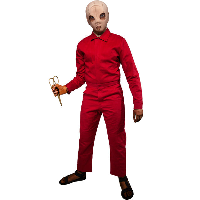 Costume.Child wearing Pluto mask, in red coveralls, holding gold scissors.