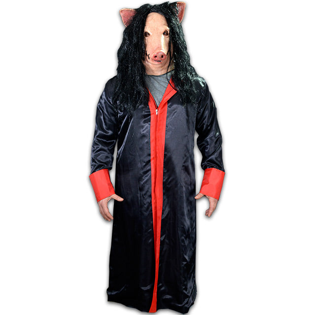 Person in pig mask, wearing satin robe, black with red trim and cuffs.