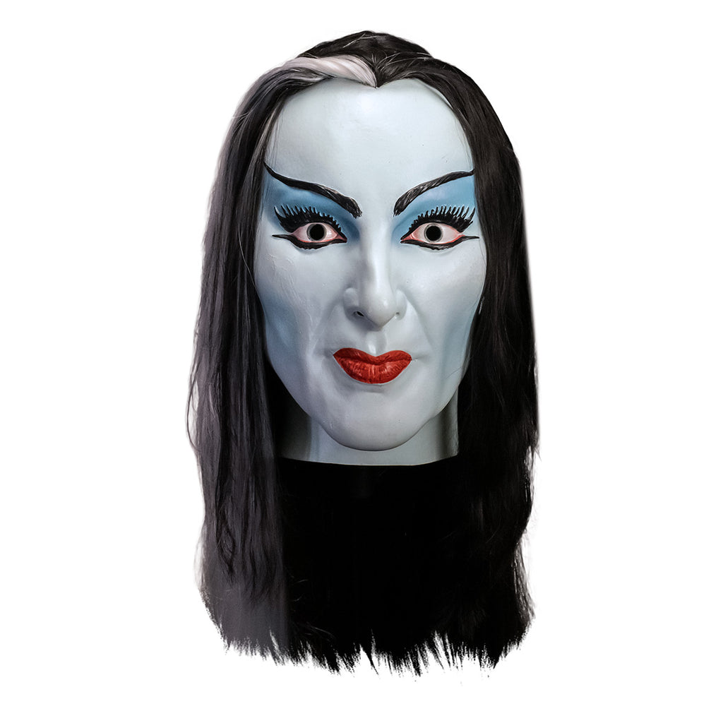 Mask, head and neck, front view. Lily Munster, white-blue skin. Black hair with white streak in middle of forehead. Thin black eyebrows, blue eyelids, big eyelashes, black winged eyeliner. Mouth closed, smiling, bright red lips. 