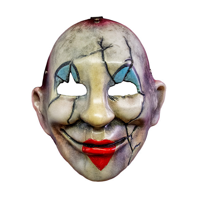 Injection plastic face mask, front view.  Distressed and dirty white face, red around edges, cracks around eyes, cheeks and left side of mouth, blue and black painted clown eyelids, red heart painted over lips of smiling mouth.