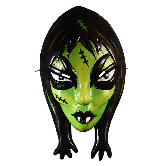 Vacuform plastic mask. Female vampire-like face. Black hair, bright green highlights. Light green face, black stitches on forehead and right cheek. High black eyebrows, black rimmed purple eyes, white pupils. Small nose, pronounced cheekbones. Black lips, two white fangs.