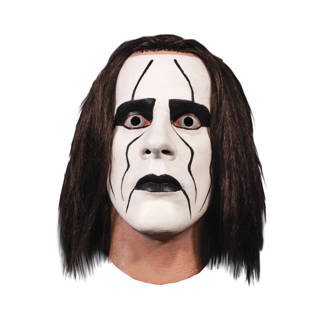 Mask, head and neck, front view.  Long dark brown hair, white face paint with black around eyes and mouth