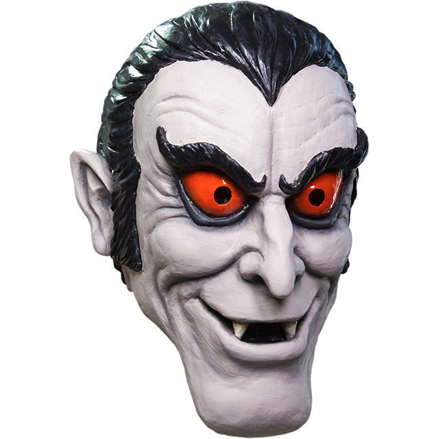 Mask, right side view. Pale gray cartoon vampire face. black hair with widow's peak, upturned black eyebrows, red-orange eyes, pointed ears, mouth open showing fangs.