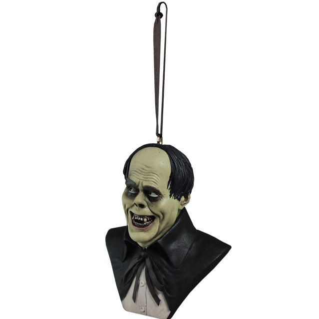 Ornament. Left side view. Phantom of the Opera Bust. Head, shoulders and upper chest of a man with balding black hair, dark circles around eyes, grinning, wearing a white shirt under a black opera cape.