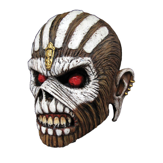 Mask, left view. Iron Maiden Eddie, brown skin, white vertical lines on top of head, Gold embellishment in center of forehead, white paint around red eyes and across cheekbones, white painted teeth on upper and lower lips, mouth open showing teeth, stretched ears with gold studs on sides.