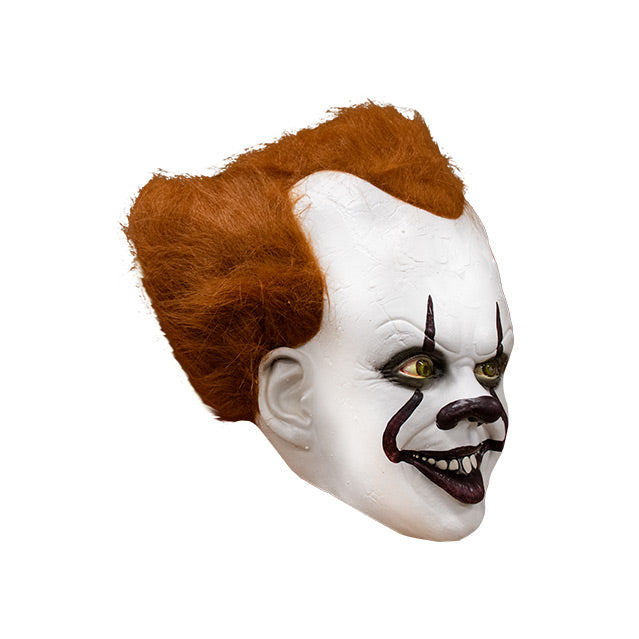 Mask, right side view. IT clown face, red hair, white skin, large forehead, Dark red nose, dark lips, creepy smile with crooked buck teeth.