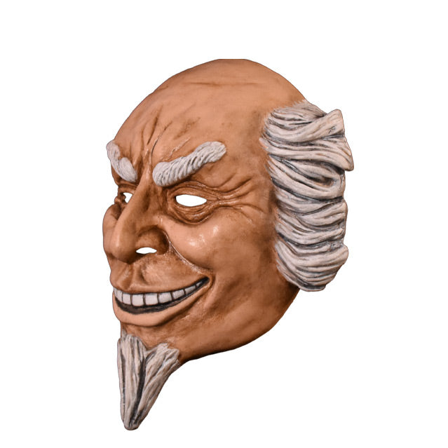 Plastic face mask. Left view. Man with wrinkled brow and around eyes, smiling showing teeth, white hair on sides of head, bald on top. white eyebrows and goatee.