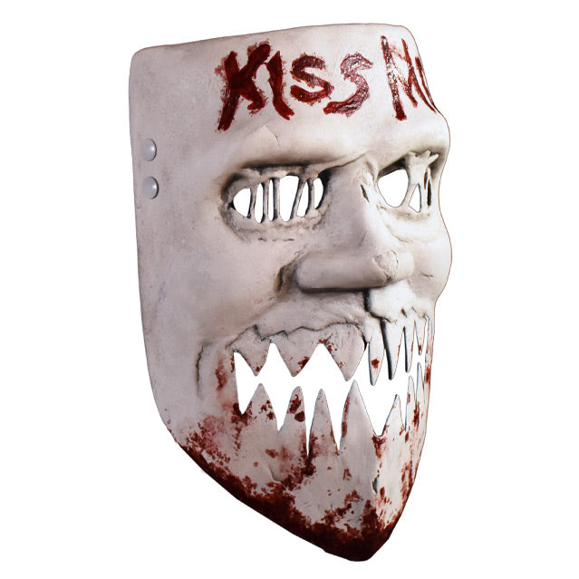 Plastic face mask, right view. White distressed finish, blood stains on chin, Large nose, mouth open jagged cut out teeth. Text written in blood on forehead reads kiss me.