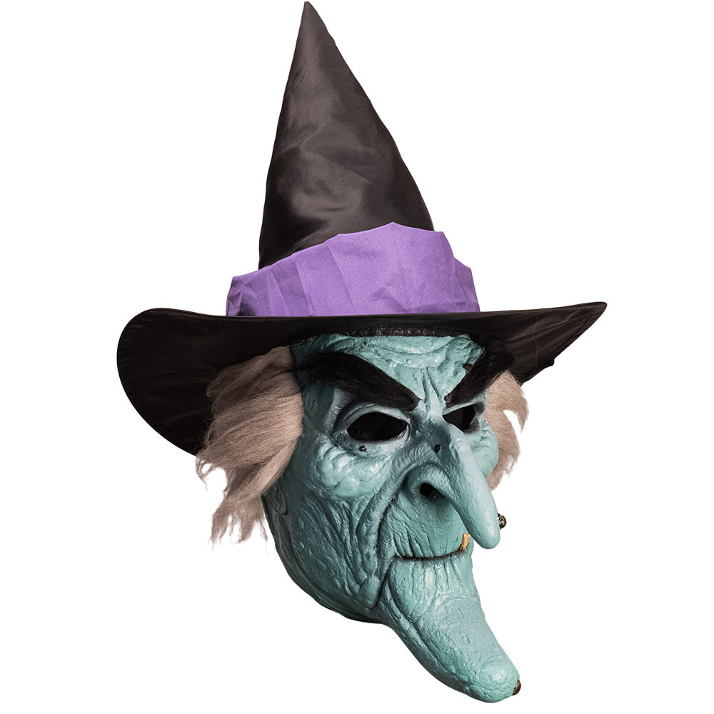 Mask, right side view. Pale green witch face with elongated chin, bushy black eyebrows and warts, gray hair, wearing black witch hat with purple band.