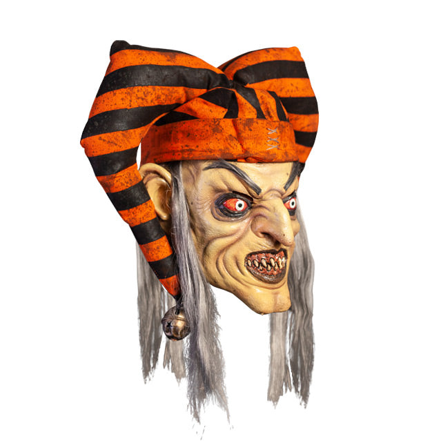 Mask, right view. Long, straight gray hair, high gray eyebrows. Large ears. Black-rimmed bloodshot eyes, pale irises. Mouth in evil grin, pink gums dirty sharp teeth, gray lips. Wearing dirty orange and black striped jester hat with bells on ends.