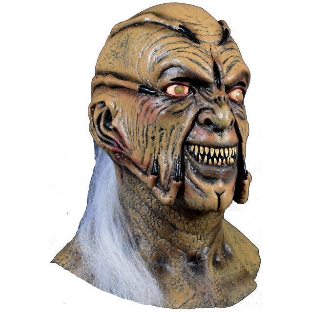 Mask, head and neck, right side view. Brown face with menacing grin and sharp teeth, 8 finger like appendages with black claws, coming around face from back of head. Cloudy eyes. cleft chin. Long white hair coming from bottom of head.