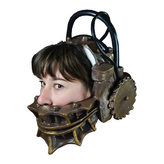 Mask, left side view, on person's head. Metallic gold trap-like device that fits around lower head and neck and over top from side to side, gears on side. black handle and cords.