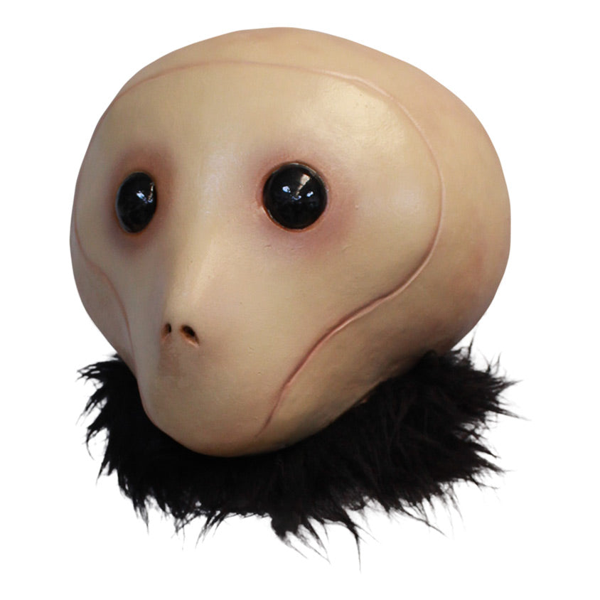 Mask, left view, head and neck. Tan head large black eyes, small nostrils, no mouth. Fur collar around neck.