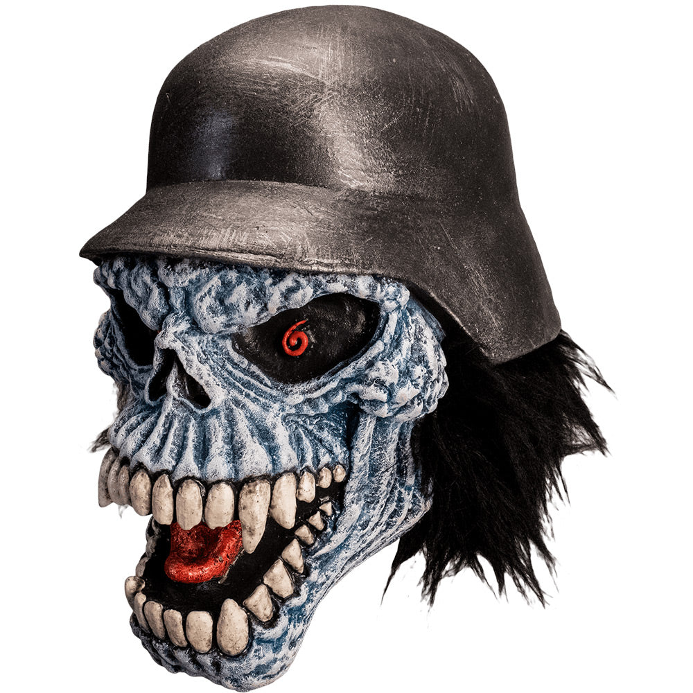 Mask, left side view. Gray lumpy skull face, shaggy black hair, black eyes with red spiral pupils, open menacing grin, many white teeth, red tongue showing. Wearing black military helmet.