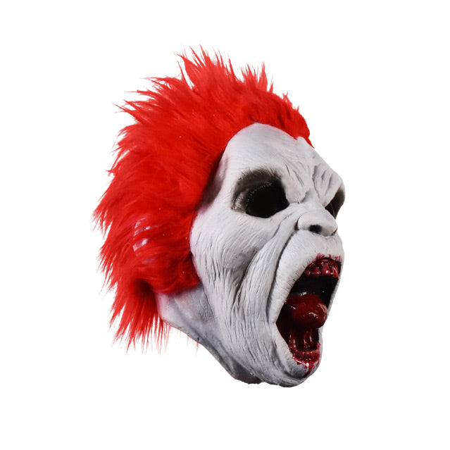 Mask, right side view. White wrinkled flesh, bright red spiked hair. Empty black eye holes, wide open snarling mouth, bloody teeth and tongue, blood around lips.