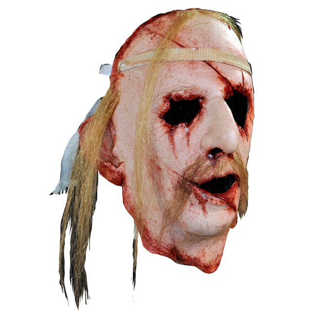 Face Mask, face and neck, right side view. Man's face, bloody with cuts and wounds around forehead, eyes, nose, mouth and neck. Sparse locks of blond hair, long blond moustache. Bandage around forehead.