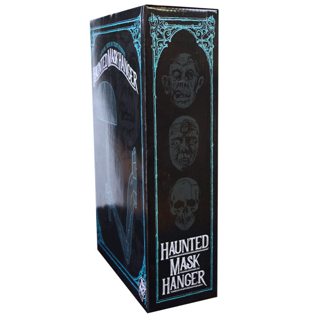 Product packaging, side.  Black box with blue decorative border, illustrations of three masks.  White text at bottom reads Haunted Mask Hanger