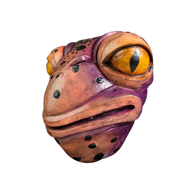 Mask, left view. Pale pink and purple toad face with black spots, large yellow eyes, 2 small nose holes between eyes. Large, wide mouth and neck.
