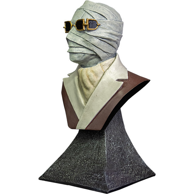 Mini bust left view. Bust of the Invisible Man, head shoulders and upper chest. Man with face covered in bandages, wearing sunglasses. White scarf around neck tucked into white collared brown coat. set on gray stone textured base.