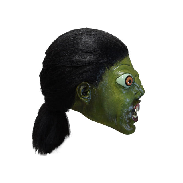 Mask, right side view. Green reptile face, long black hair pulled back in a ponytail, large orange eyes, small nose, open mouth with 2 large fangs and showing bottom teeth.