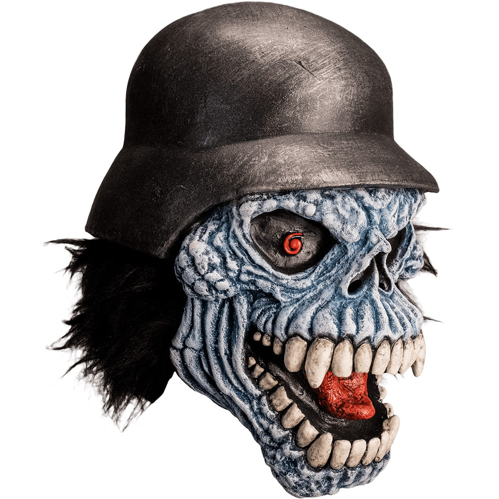 Mask, right side view. Gray lumpy skull face, shaggy black hair, black eyes with red spiral pupils, open menacing grin, many white teeth, red tongue showing. Wearing black military helmet.