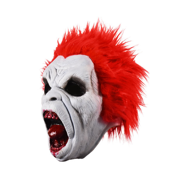 Mask, left view. White wrinkled flesh, bright red spiked hair. Empty black eye holes, wide open snarling mouth, bloody teeth and tongue, blood around lips.