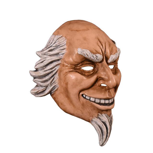 Plastic face mask. Right view. Man with wrinkled brow and around eyes, smiling showing teeth, white hair on sides of head, bald on top. white eyebrows and goatee.