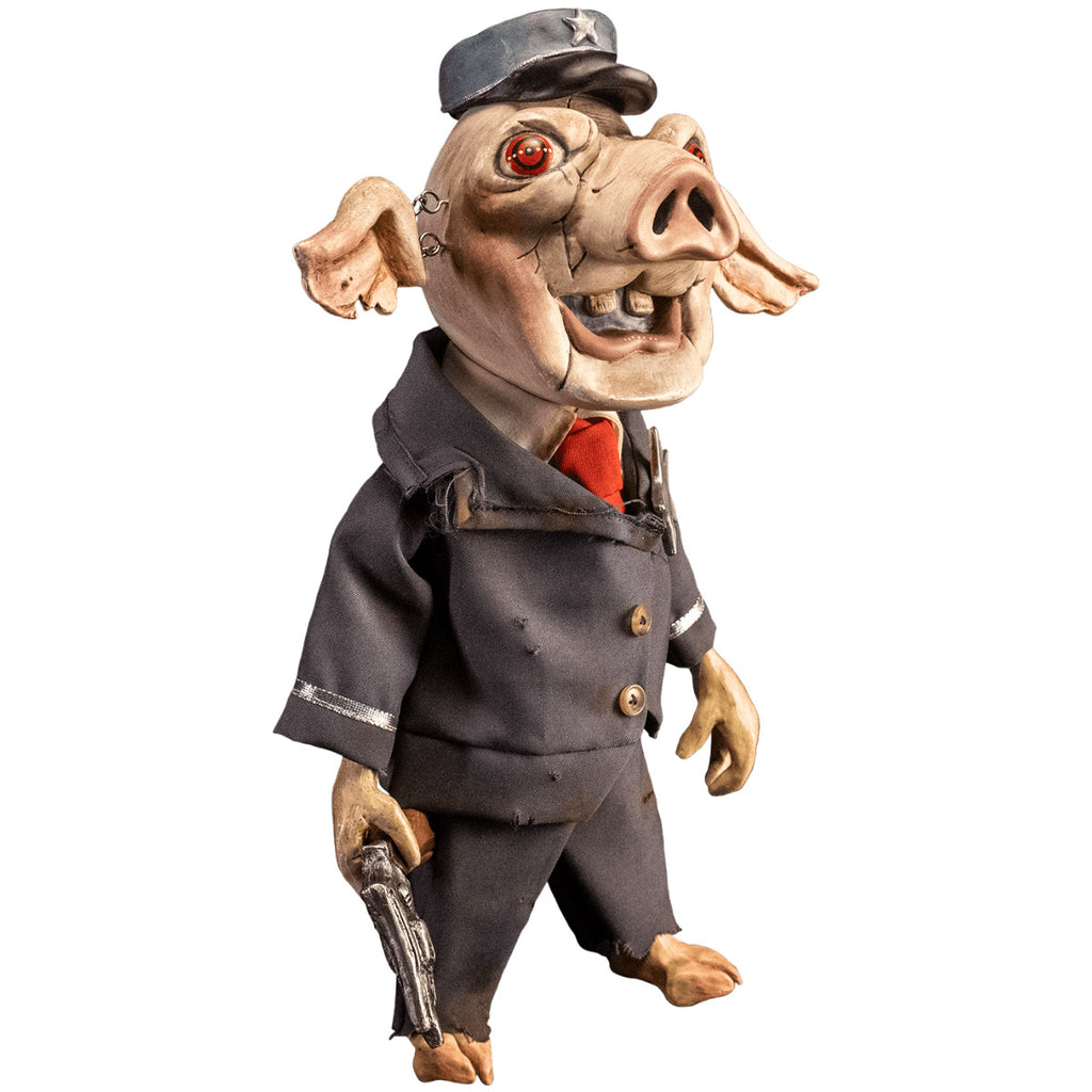 Mr. Snuggles puppet prop, right side view. Pink pig face, red eyes, open mouth with two buck teeth, ears attached with metal links, blue hat with silver star. Wearing distressed blue suit, with silver trim and silver star, 2 gold buttons, dirty white shirt, red necktie, cloven hoof pig feet. Right hand holding wooden handled silver pistol.