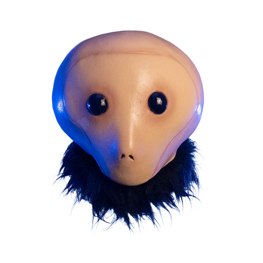 Mask, front view, head and neck. Under dramatic blue lighting, Tan head large black eyes, small nostrils, no mouth. Fur collar around neck.