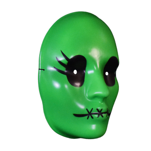 Vacuform plastic face mask, right view. Bright green face, large black eyes with 3 eyelashes on the sides, 4 black x stitches across lips.