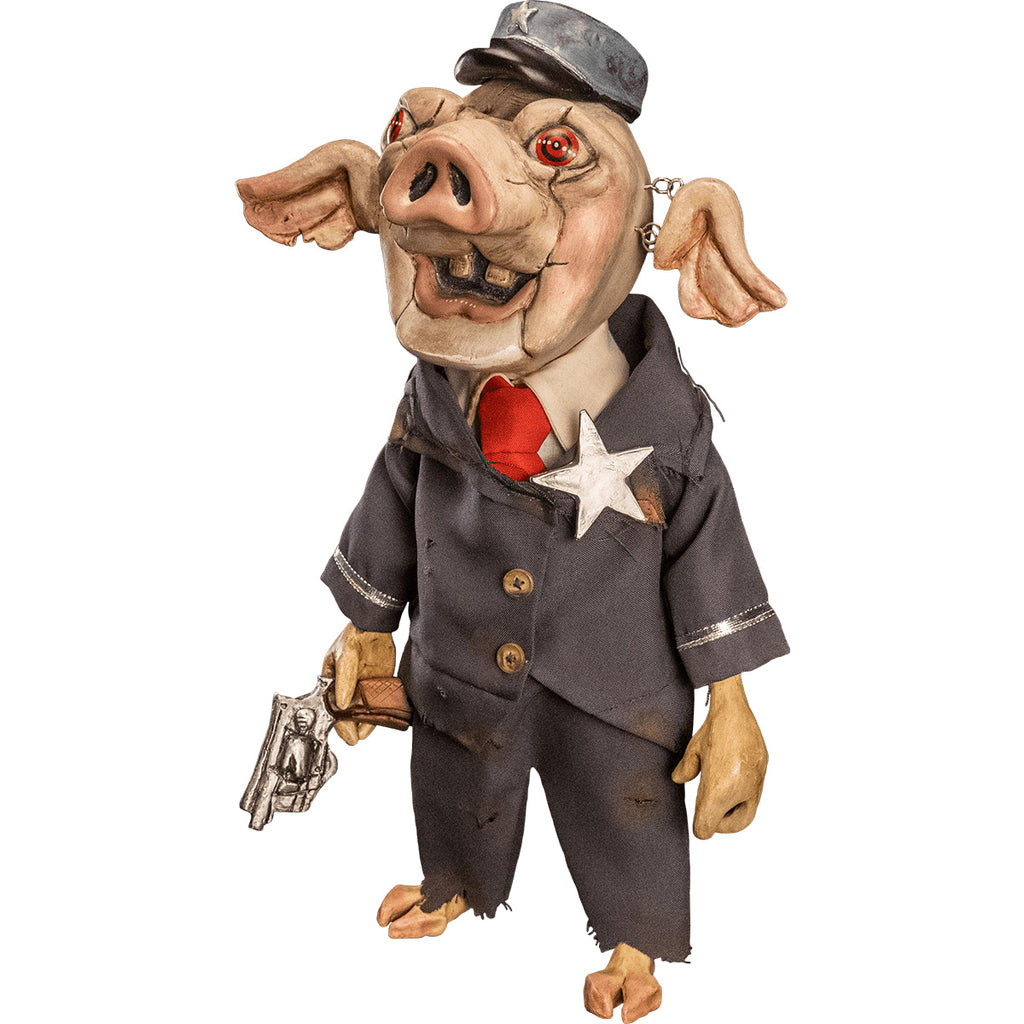 Mr. Snuggles puppet prop, left side view. Pink pig face, red eyes, open mouth with two buck teeth, ears attached with metal links, blue hat with silver star. Wearing distressed blue suit, with silver trim and silver star, 2 gold buttons, dirty white shirt, red necktie, cloven hoof pig feet. Right hand holding wooden handled silver pistol.