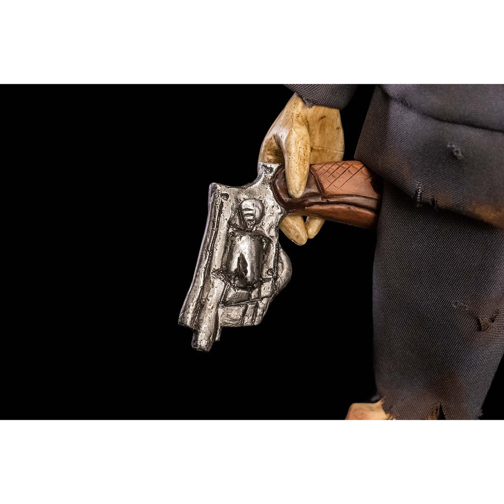 Black background. Close up of Mr. Snuggles puppet right hand holding wooden handled silver pistol.