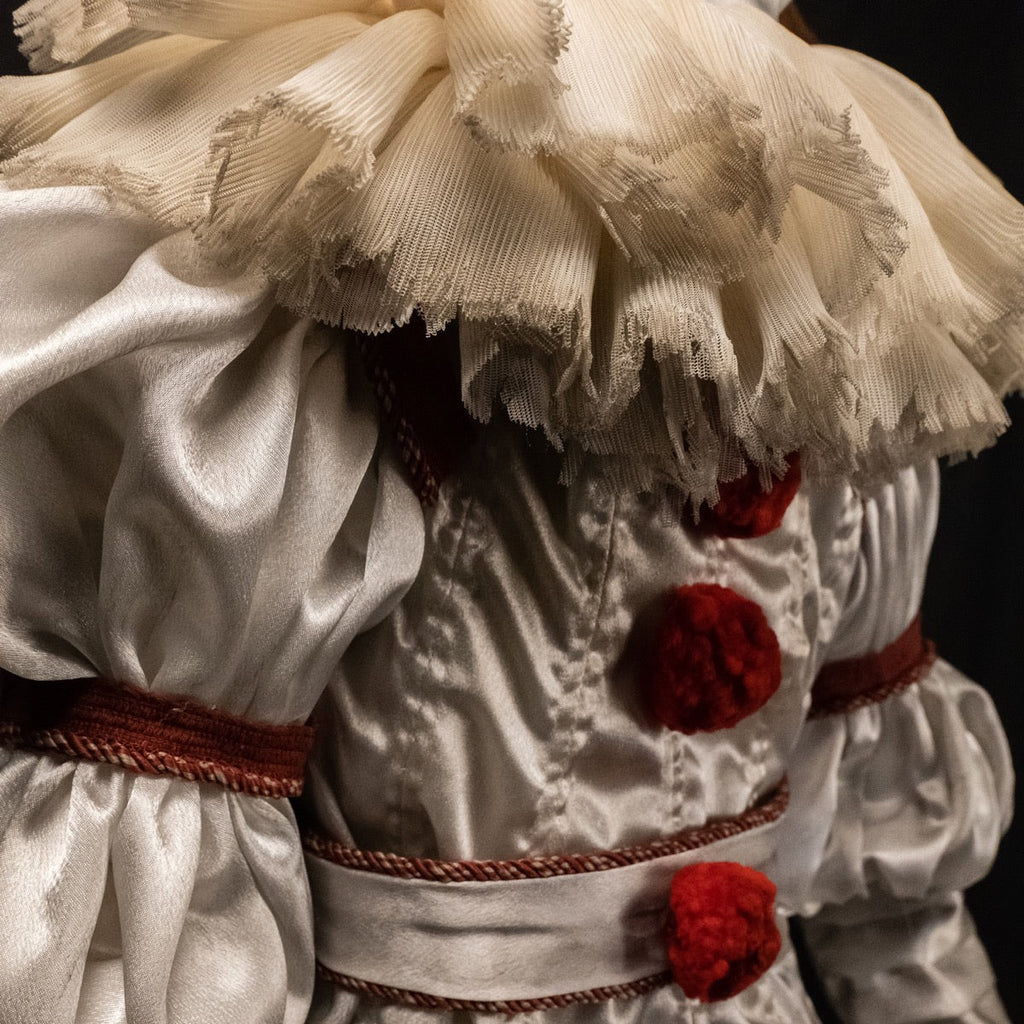 Close up of costume, dirty neck ruffle, red trim on sleeves and belt, red pompoms.