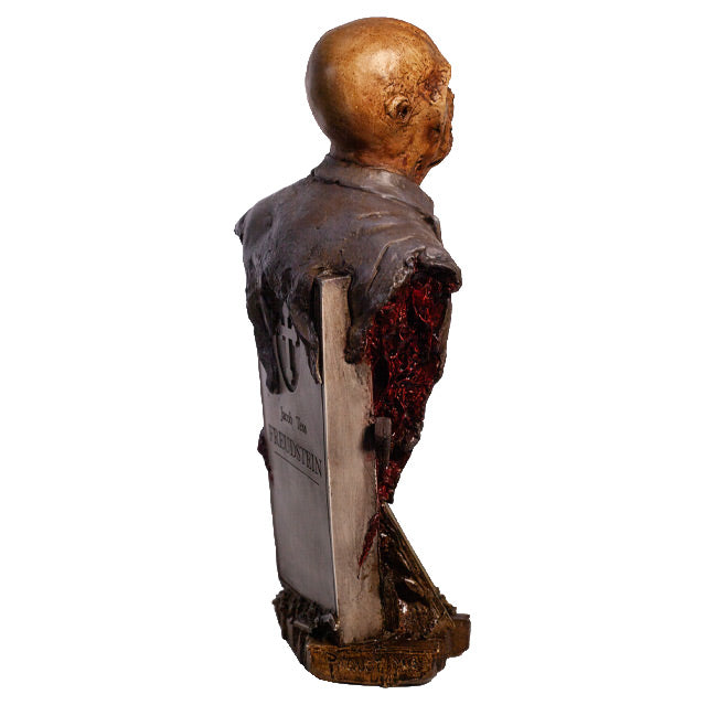 Zombie bust, back right side view, head, shoulders and chest. Orange-hued shriveled flesh, wearing filthy and gory blue doctor's coat. Gore coming from bottom of torso. Gray tombstone in back, cross in circle at top, set on wood look base.