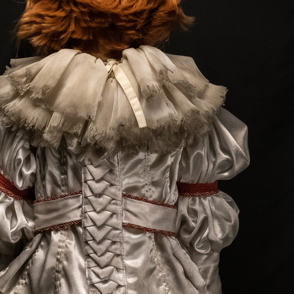 Close up of back of costume, dirty neck ruffle, red trim on sleeves and belt.