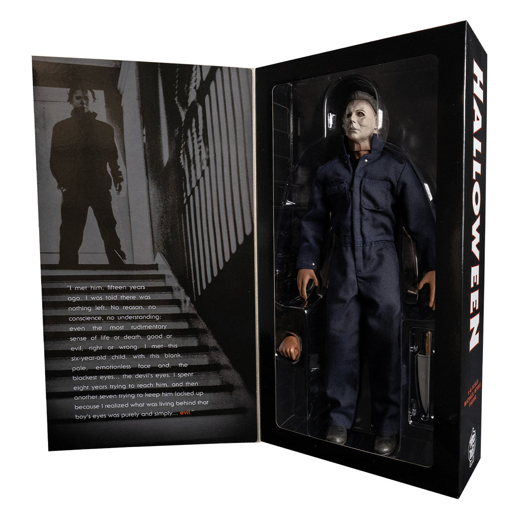 Product packaging open view. Black box. left side, black and white image of Michael Myers standing at the top of a set of stairs.  Right side, figure and accessories in clear window.  Text on side of box reads Halloween. 