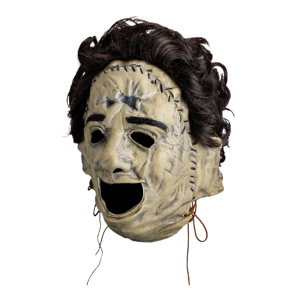 Mask, left view, short brown bushy hair, black eyebrows, skin is sewn together, stitches around forehead and ears, open space for mouth.