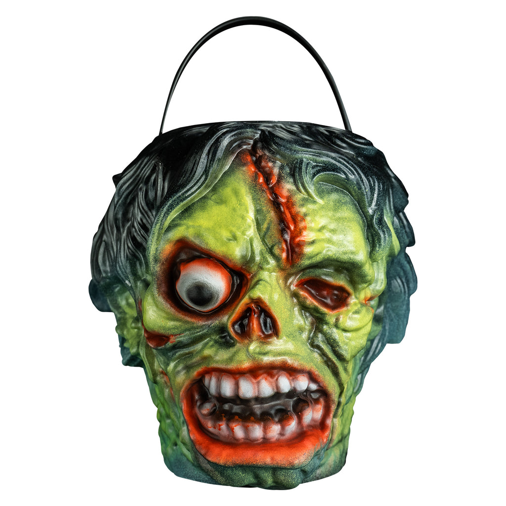 candy pail, front view. Black bushy hair, Green flesh, wrinkled and wounded. Bulging, bloodshot right eye, missing left eye and nose. Open snarling mouth with crooked teeth., black handle at top.