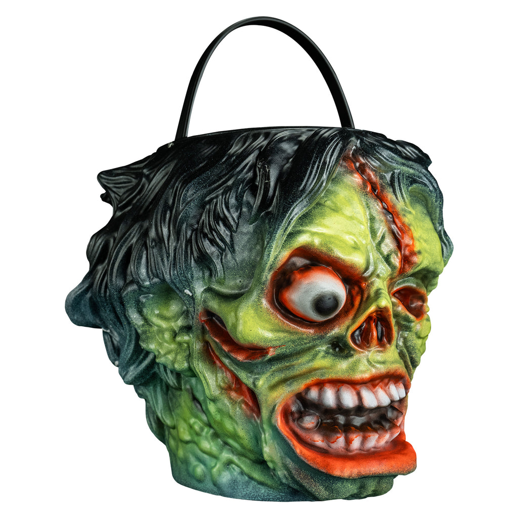 candy pail, right view. Black bushy hair, Green flesh, wrinkled and wounded. Bulging, bloodshot right eye, missing left eye and nose. Open snarling mouth with crooked teeth. black handle at top.