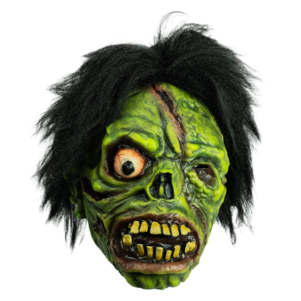 Mask front view. Black bushy hair, Green flesh, wrinkled and wounded. Bulging, bloodshot right eye, missing left eye and nose. Open snarling mouth with yellow crooked teeth.