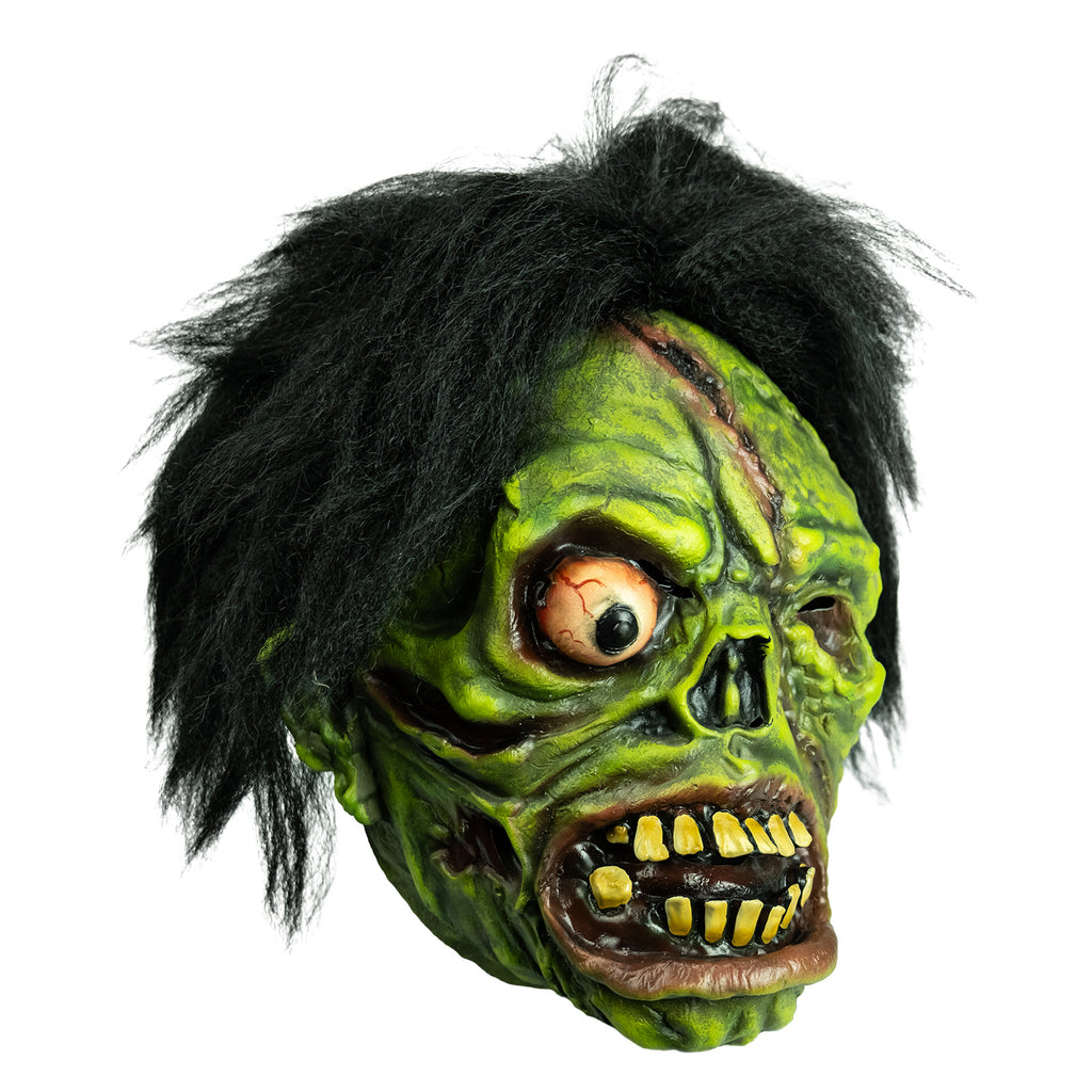 Mask right view. Black bushy hair, Green flesh, wrinkled and wounded. Bulging, bloodshot right eye, missing left eye and nose. Open snarling mouth with yellow crooked teeth.