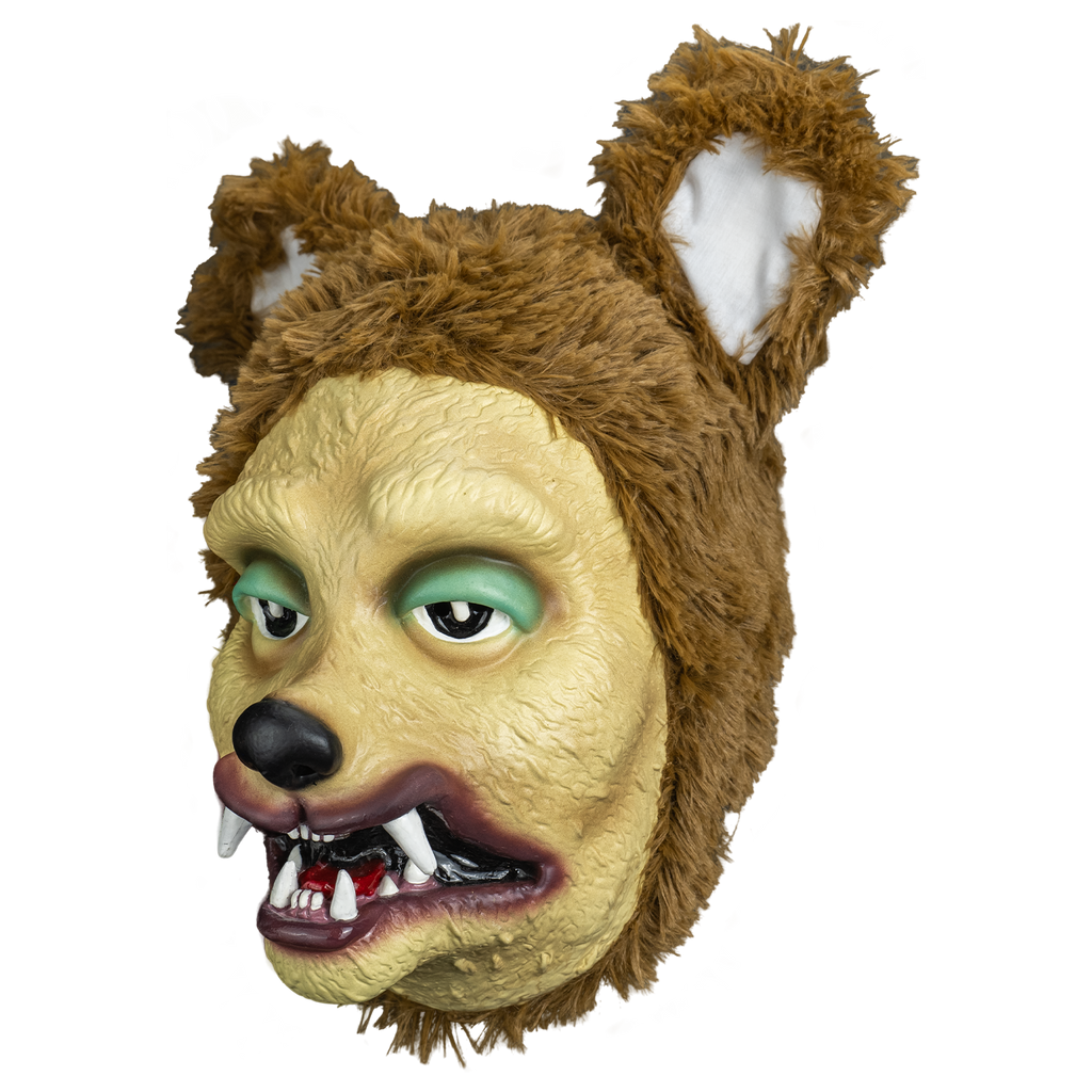 mask left view.  stylized dog face tan, green eyelids, black nose, purple lips, mouth open showing red tongue and crooked canine like teeth  surrounded with plush fur large brown and white ears on top of head.