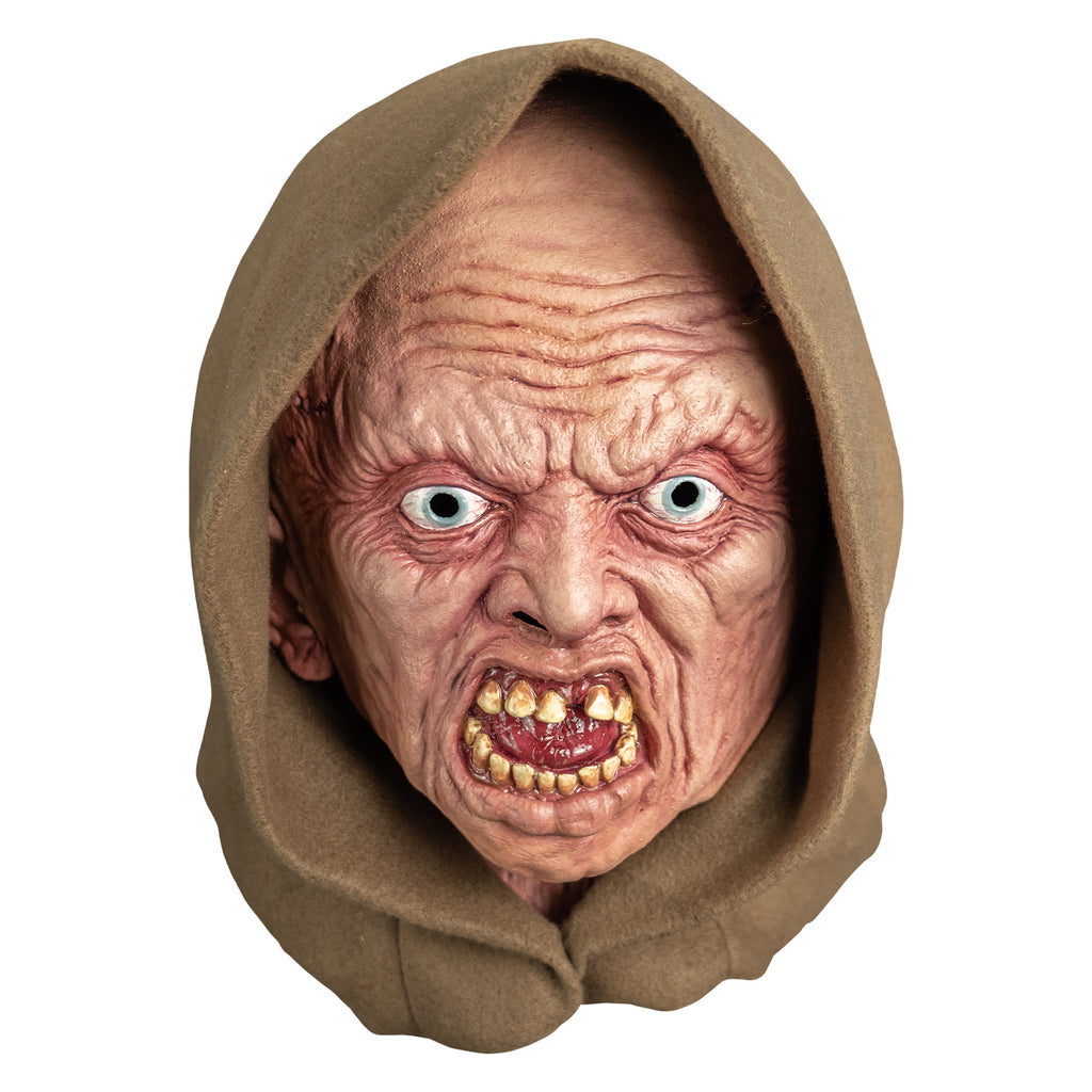 mask, front view.  wearing tan hood.  pink highly wrinkled flesh.  no eyebrows, pale blue irises,  mouth open in a snarl showing crooked yellowed teeth an shiny wet looking red tongue.