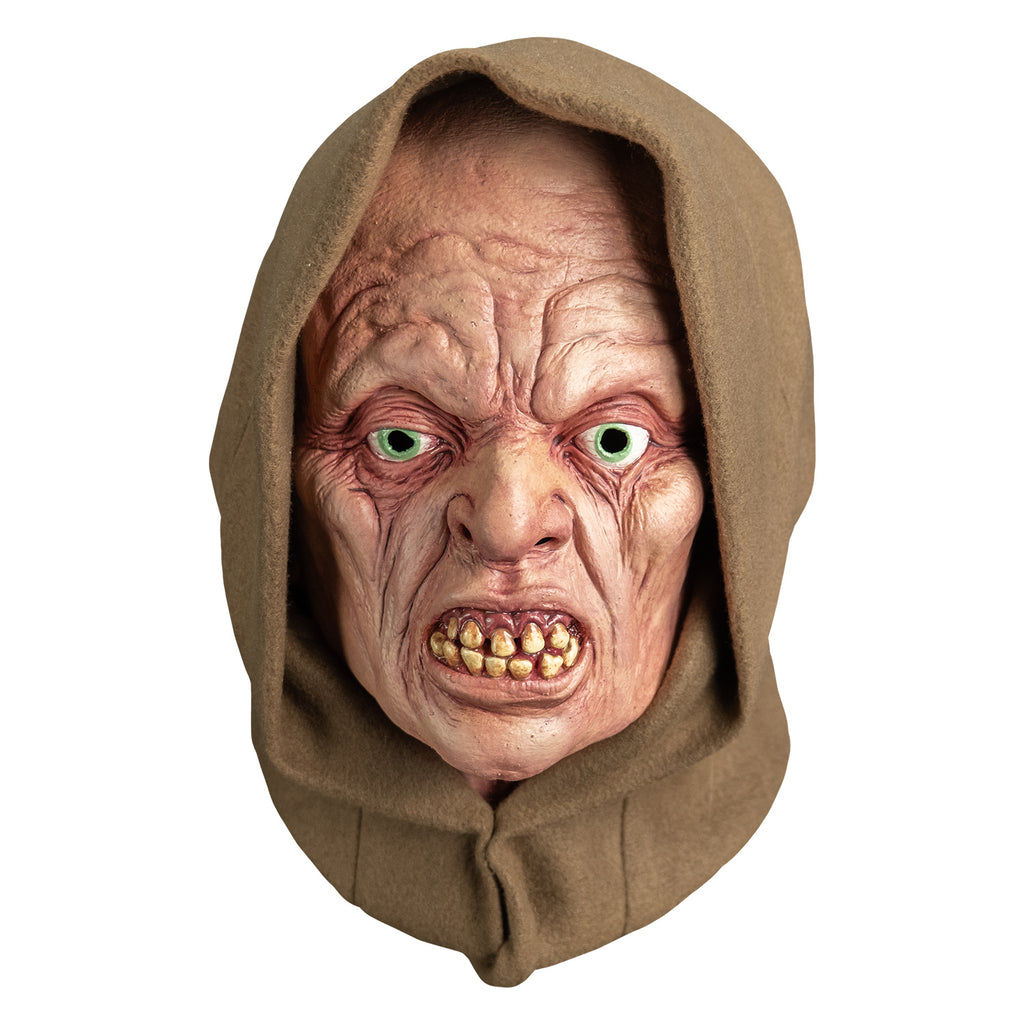mask, front view. wearing tan hood. pink wrinkled flesh. no eyebrows, pale blue irises, lips open showing crooked yellowed teeth.