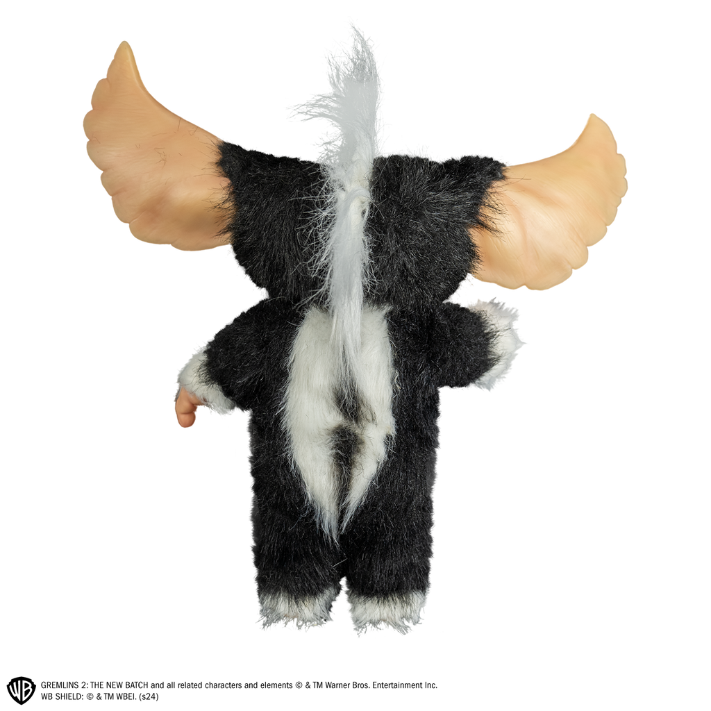 Mohawk mogwai prop, back view, full body, black and white fur, white stripe mohawk in center of head, white stripe down back, large pointed tan ears.  Hairless hands and feet. 