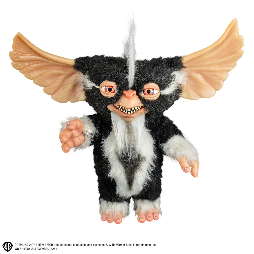 Mohawk mogwai prop, front view, full body, black and white fur, white stripe mohawk in center of head. toothy smiling mouth, large brown eyes, large pointed tan ears.  Hairless hands and feet. 