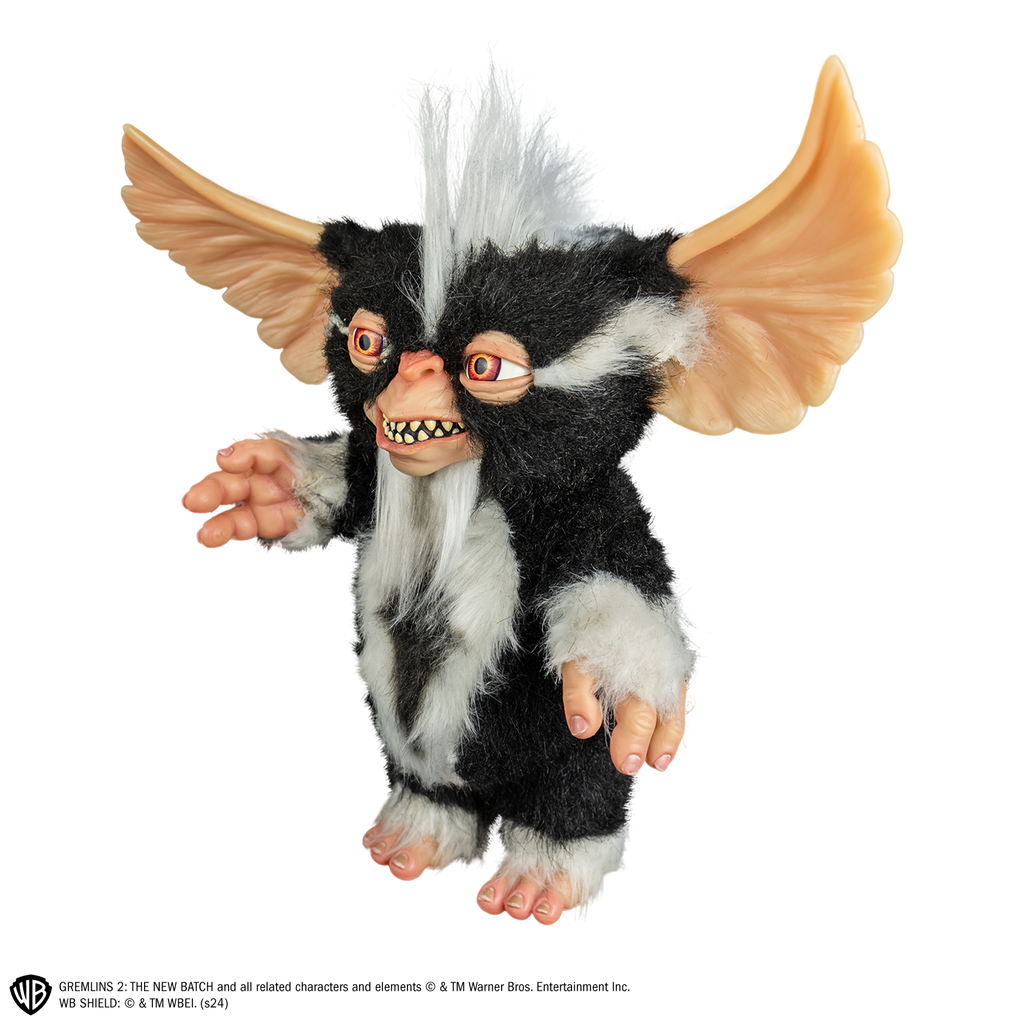 Mohawk mogwai prop, left view, full body, black and white fur, white stripe mohawk in center of head. toothy smiling mouth, large brown eyes, large pointed tan ears.  Hairless hands and feet. 