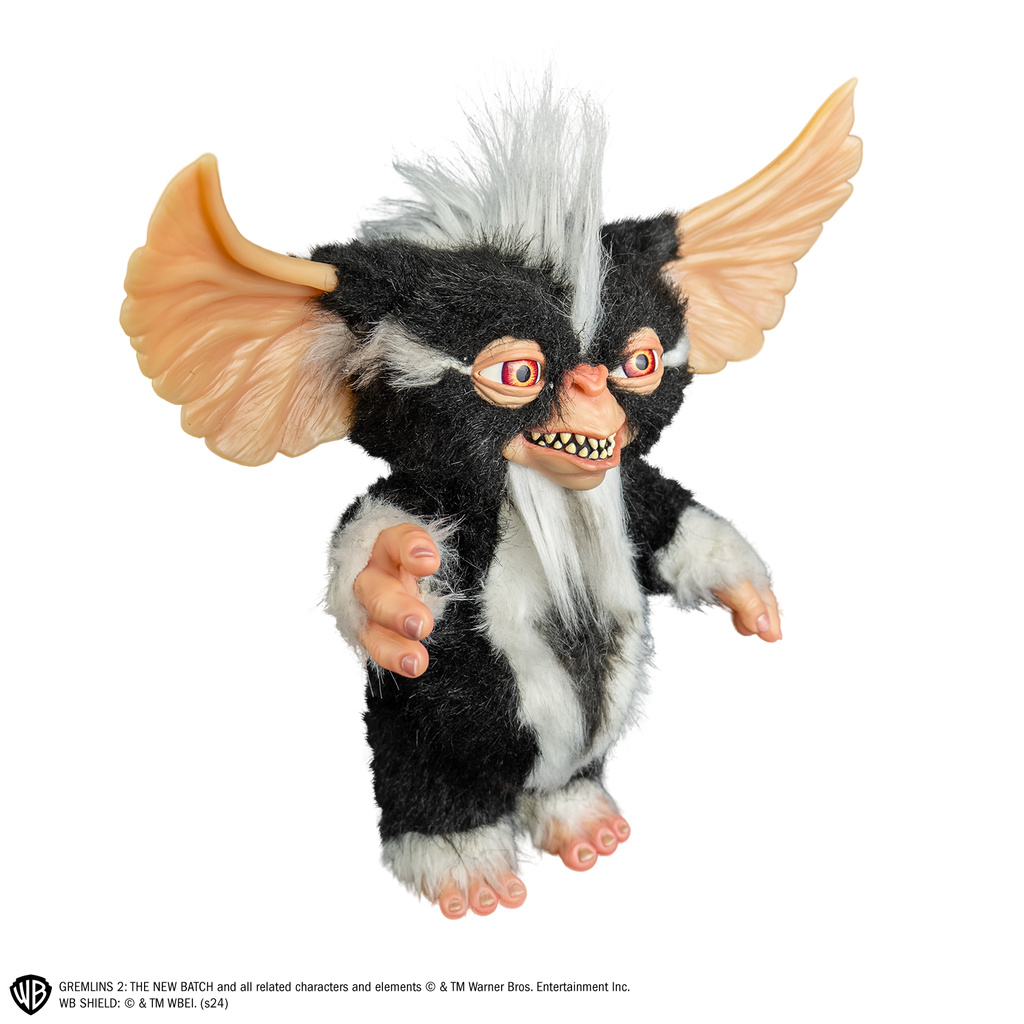 Mohawk mogwai prop, right view, full body, black and white fur, white stripe mohawk in center of head. toothy smiling mouth, large brown eyes, large pointed tan ears.  Hairless hands and feet. 