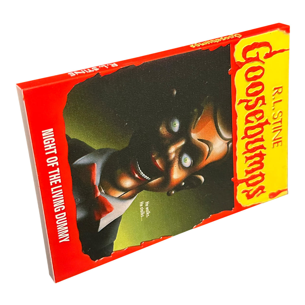 Magnet. Has the appearance of a book cover. Illustration of a menacing ventriloquist dummy with a black and green background. Yellow banner at top, red text reads R.L. Stine, Goosebumps. White text on illustration reads He walks, He stalks. Red border at bottom, white text reads Night of the Living Dummy.
